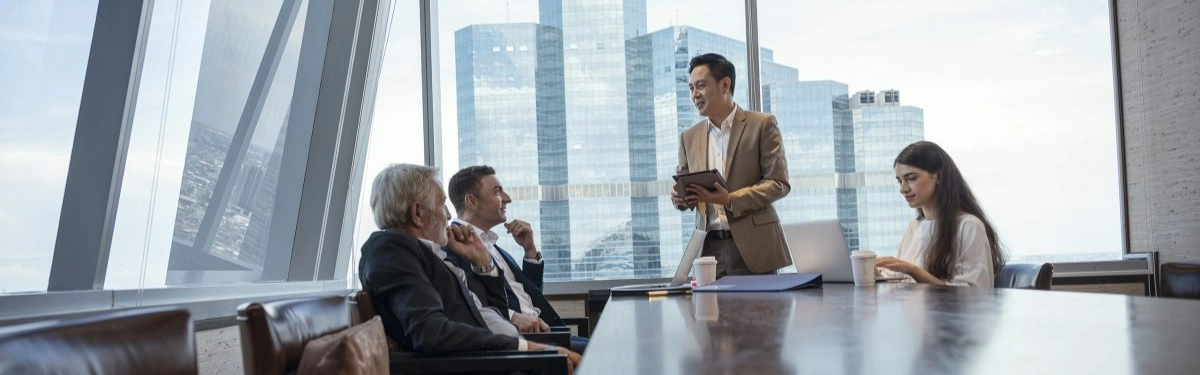 colleghi che fanno una riunione in un ufficio vetrato con dietro skyline di grattacieli