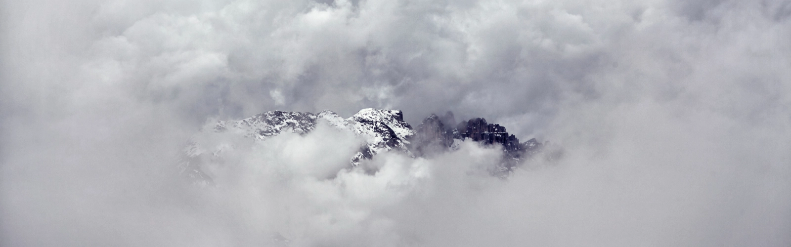 vetta di una montagna che esce dalle nuvole che riempiono il cielo