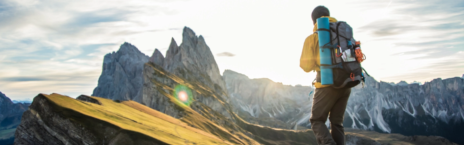 An image of a person with a backpack hiking looking out over hills and a mountain range
