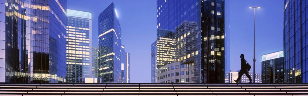 skyline di palazzi di notte con un signore che cammina sulla strada